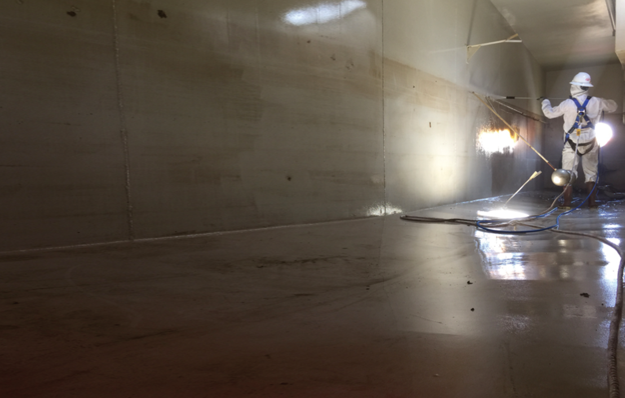 Frac tank cleaning — worker pressure washing interior